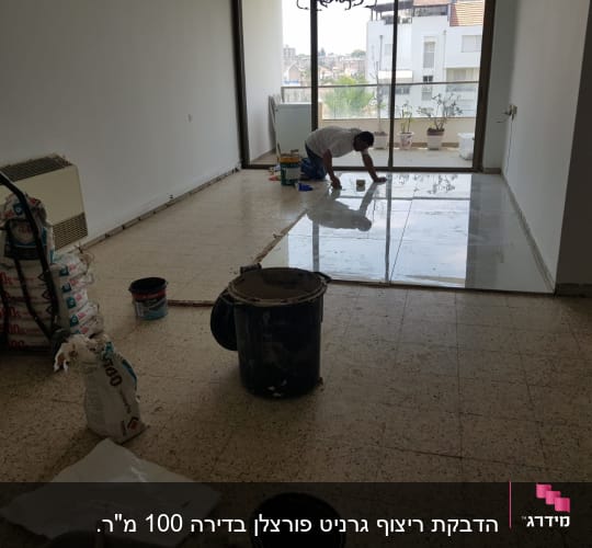 עובד מתקין אריחי רצפה חדשים בחדר עם כלים וחומרים
